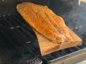 Salmon cooking on a plank of wood in a barbeque