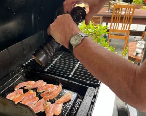 Small trout fillet portions being seasoned on a BBQ hotplate